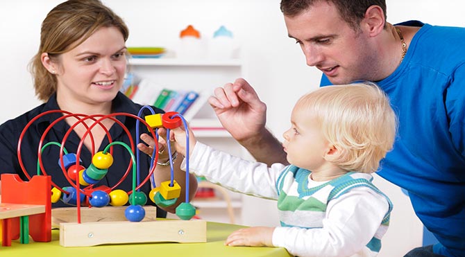 A Mom and Dad around a child playing a game