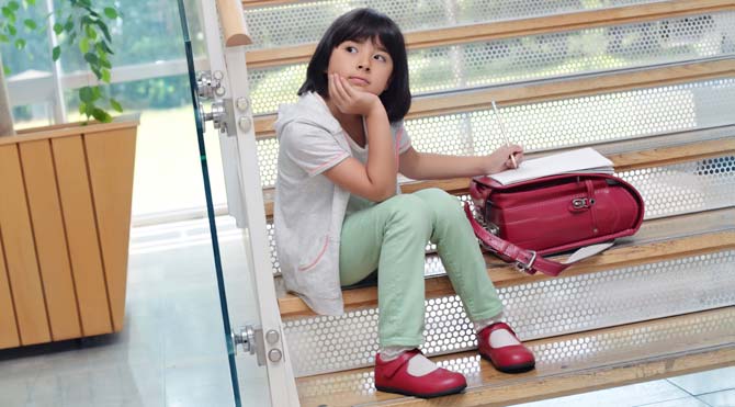 Thoughtful girl writing on the stairs